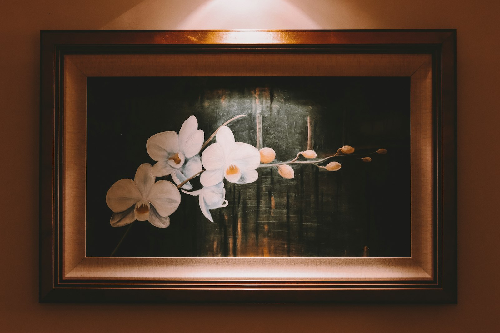 Framed floral artwork lit by a picture light