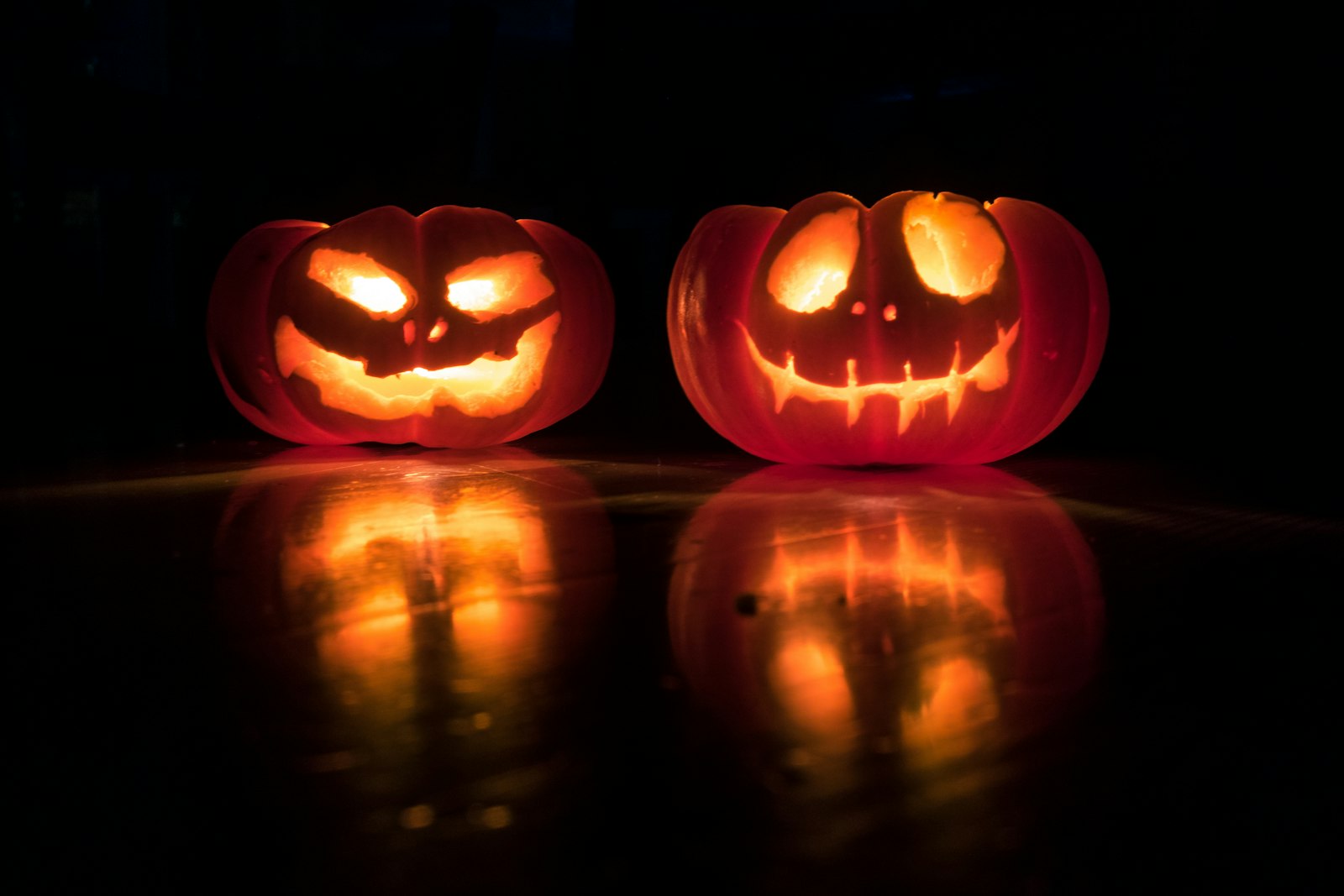 Two carved pumpkins glowing in the dark