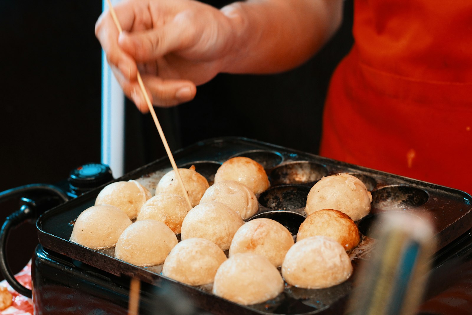 Takoyaki balls being turned on a cooking griddle