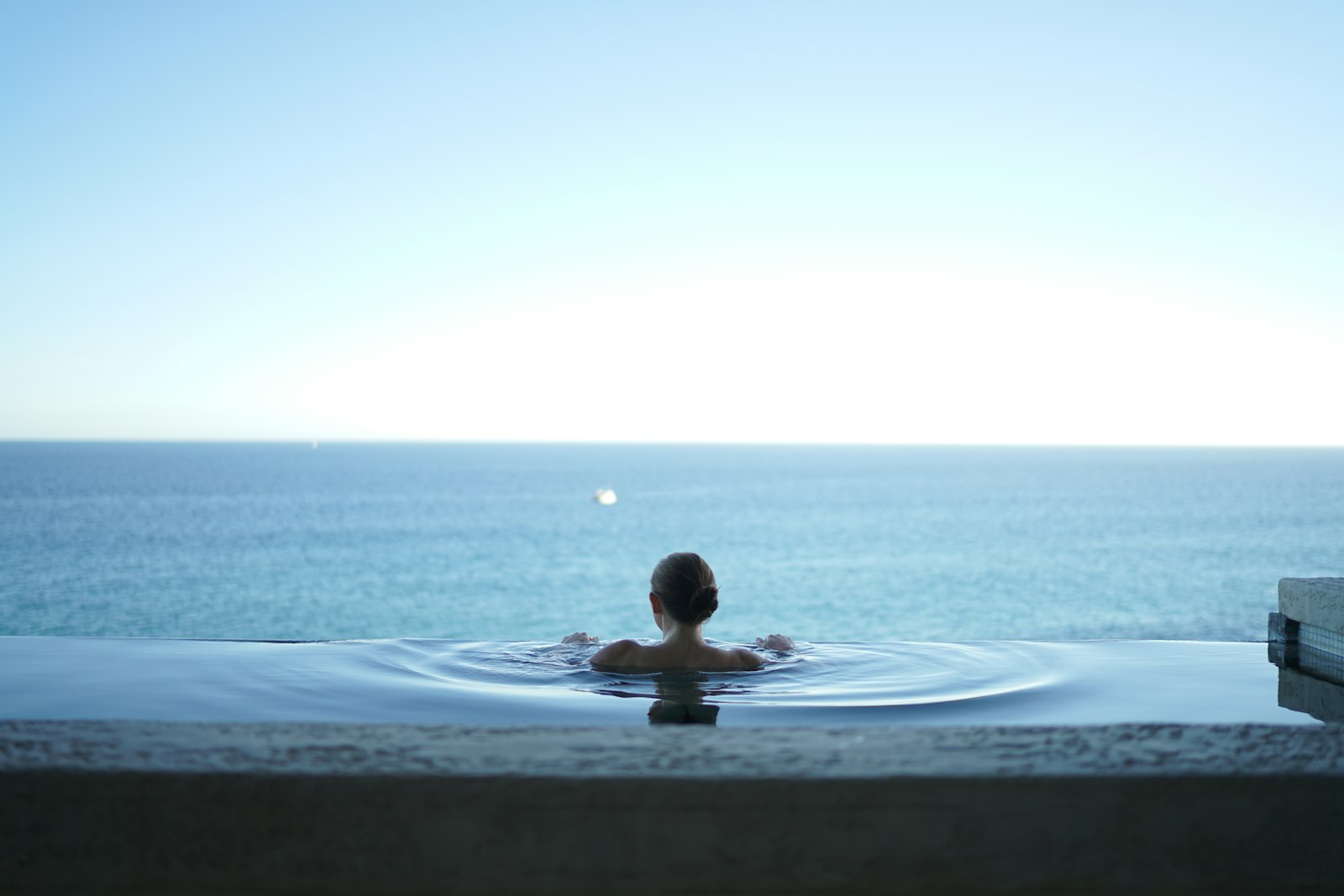 Guest relaxing in an infinity pool overlooking the sea