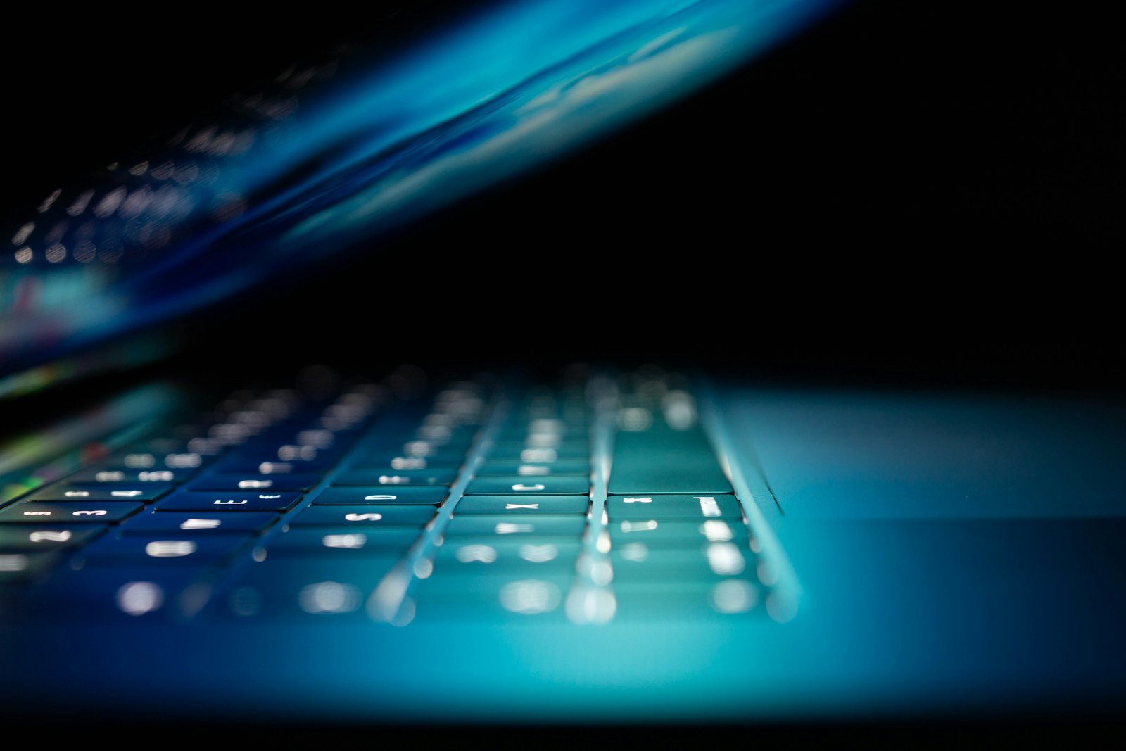 Close-up of a laptop keyboard illuminated in blue