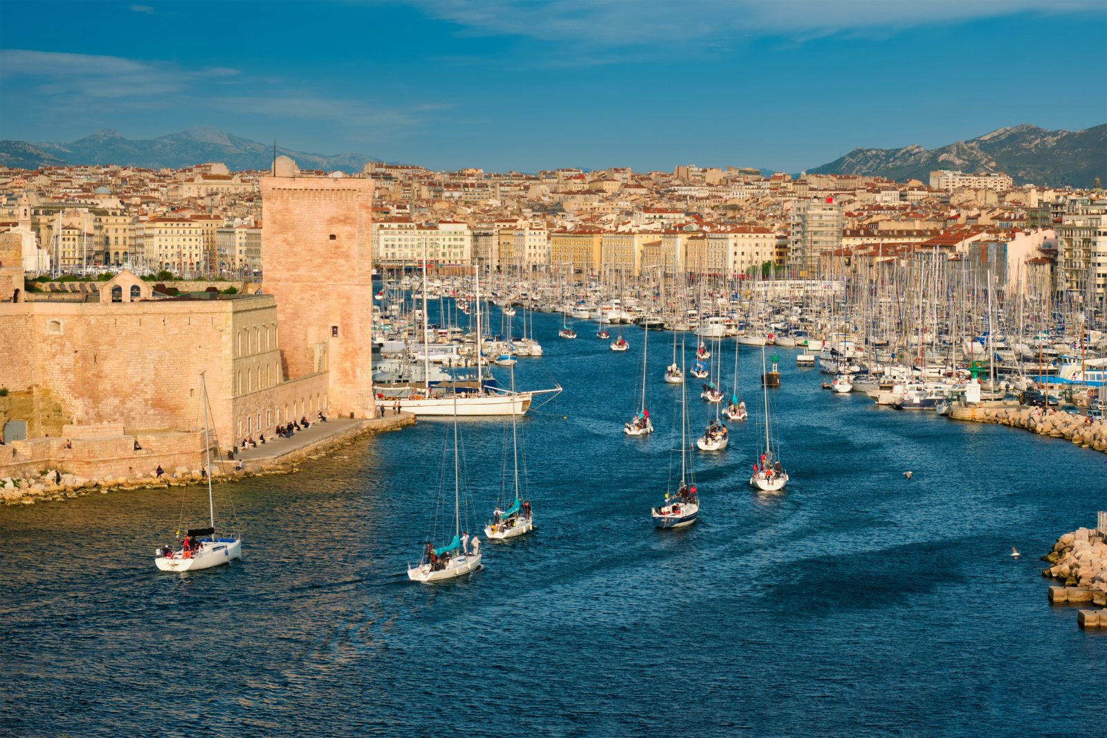 Yachts entering the Old Port of Marseille at sunset beside Fort Saint Jean