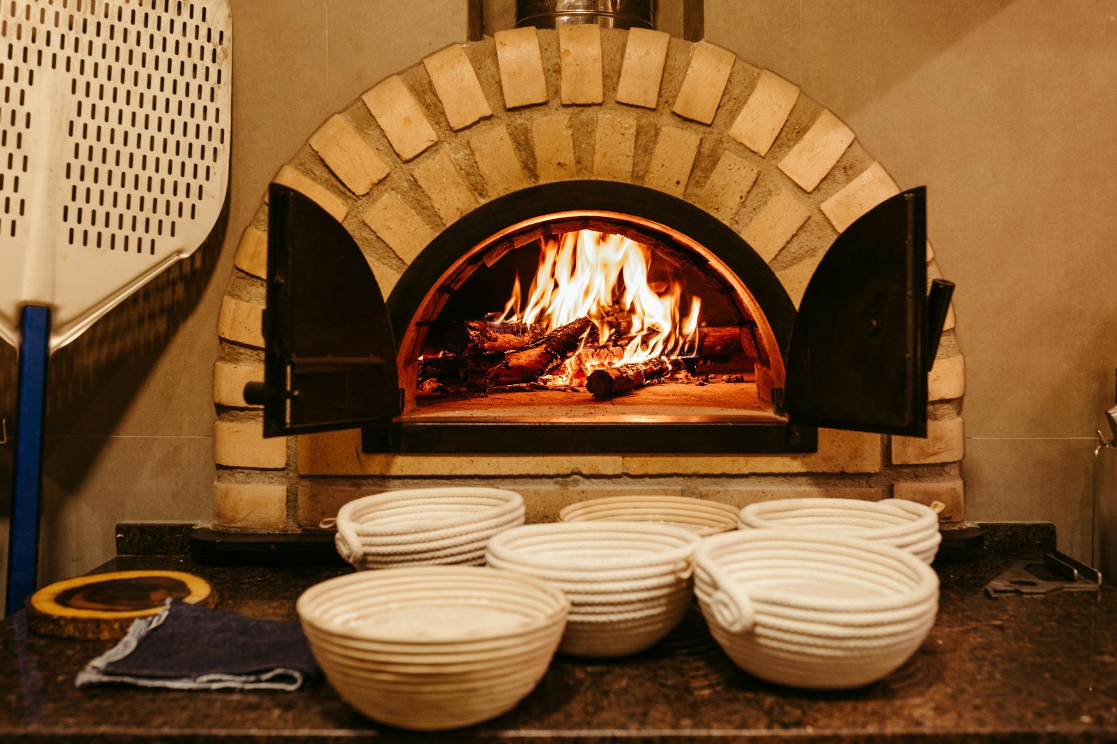 White bowls stacked in front of a brick pizza oven