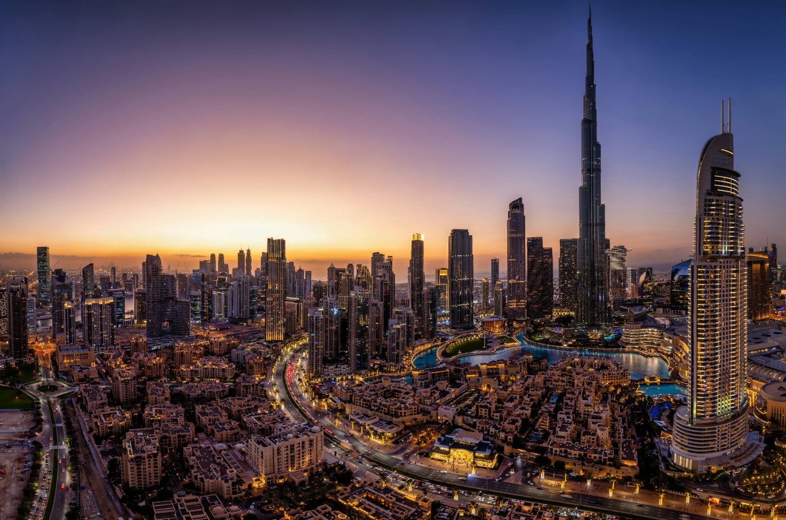 Panoramic view of the illuminated downtown Dubai skyline at dusk